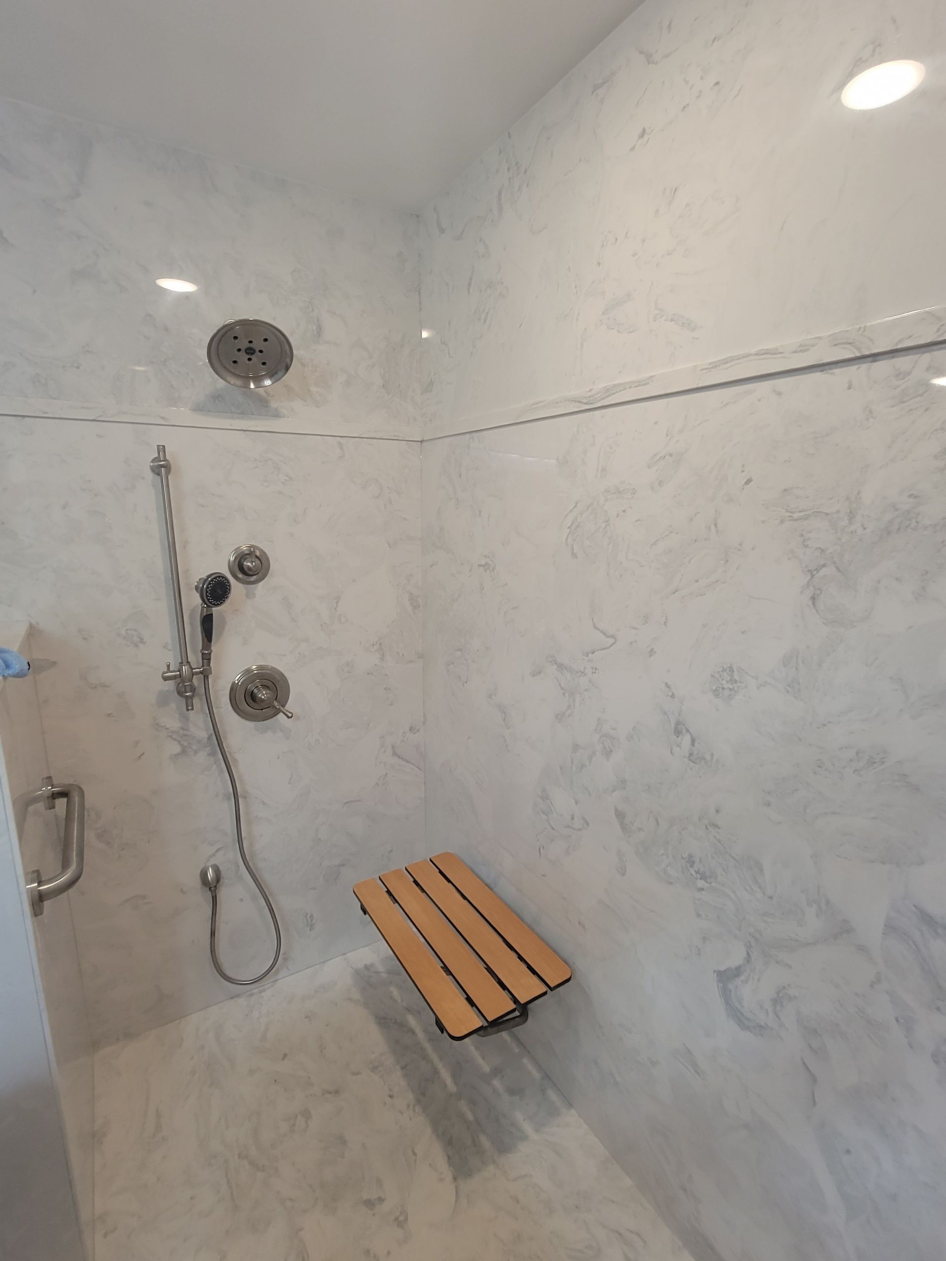 A bathroom with a walk in shower and a wooden bench