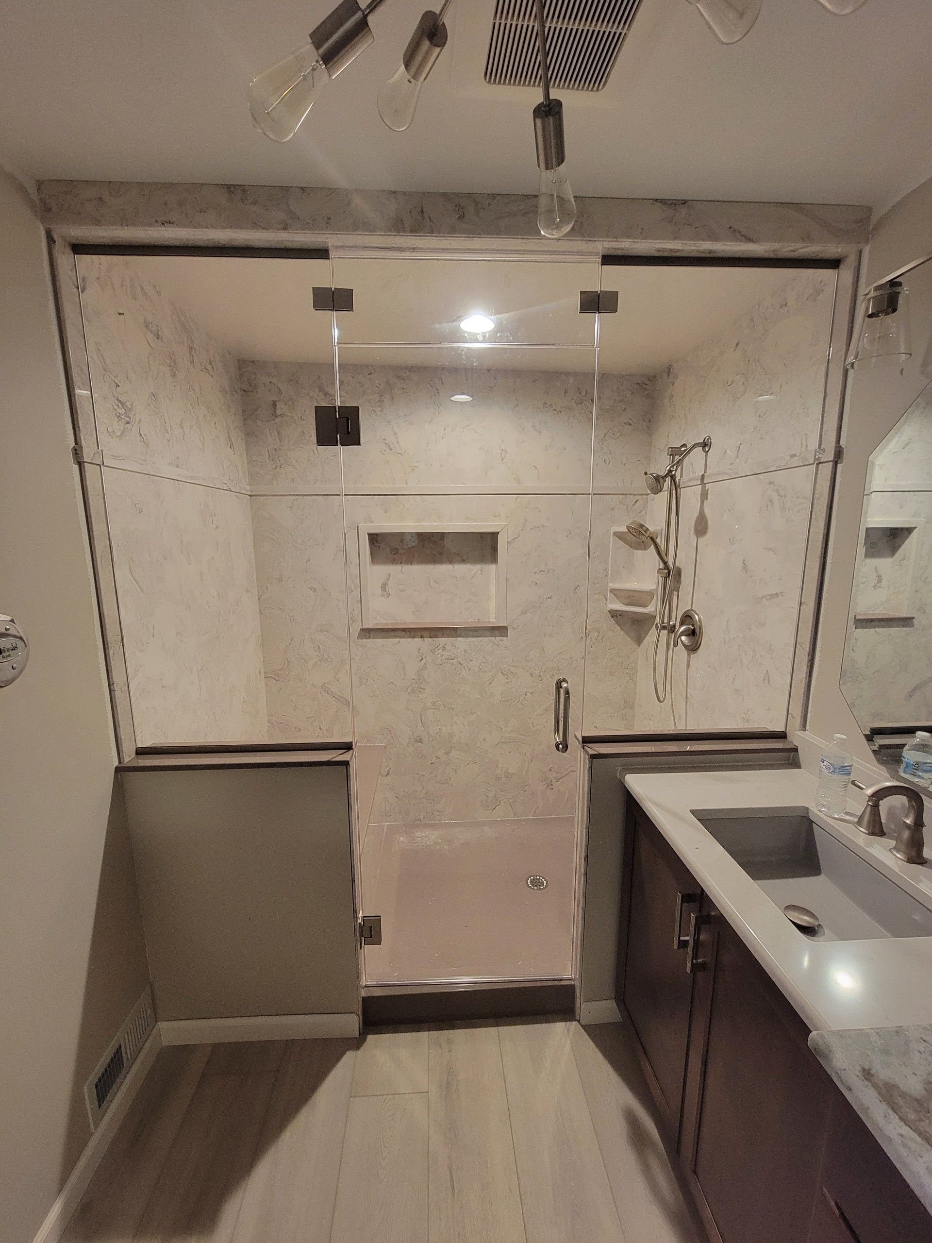 A bathroom with a shower, sink and mirror.