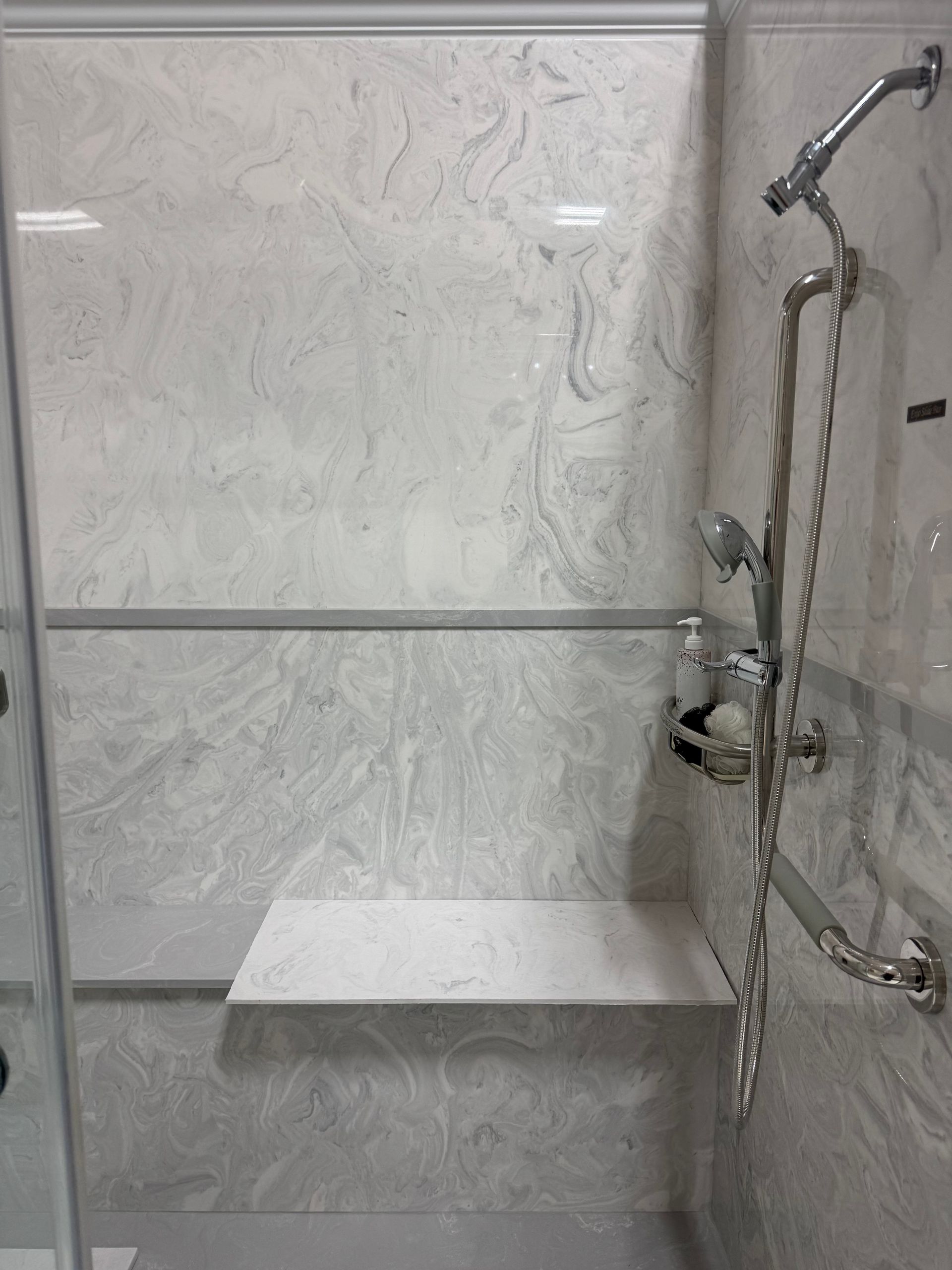 There is a shower with a bench and a shower head.