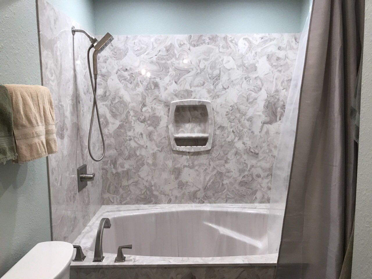 A bathroom with a tub, shower and toilet.