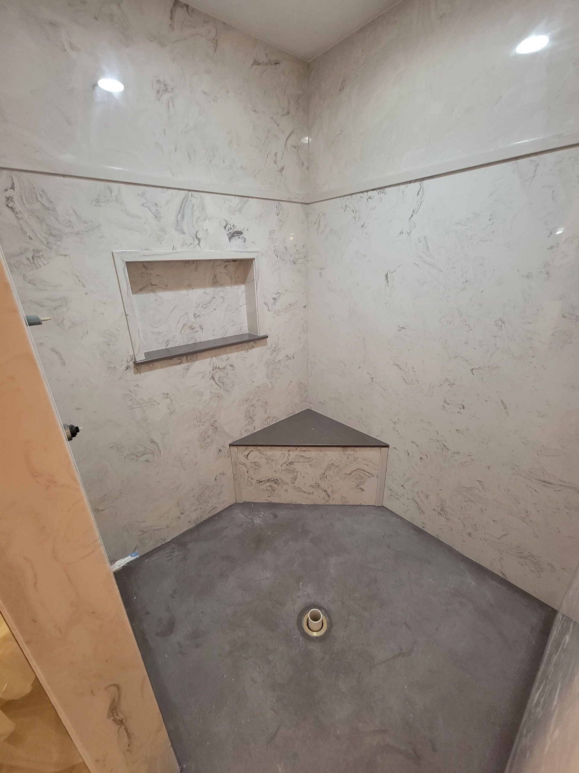 A bathroom with a walk in shower and a corner shelf.