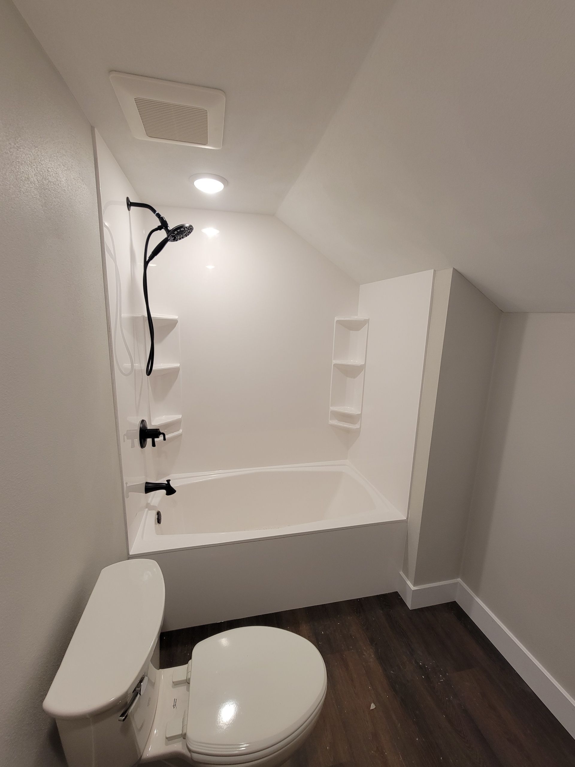 A bathroom with a walk in shower and a corner shelf.