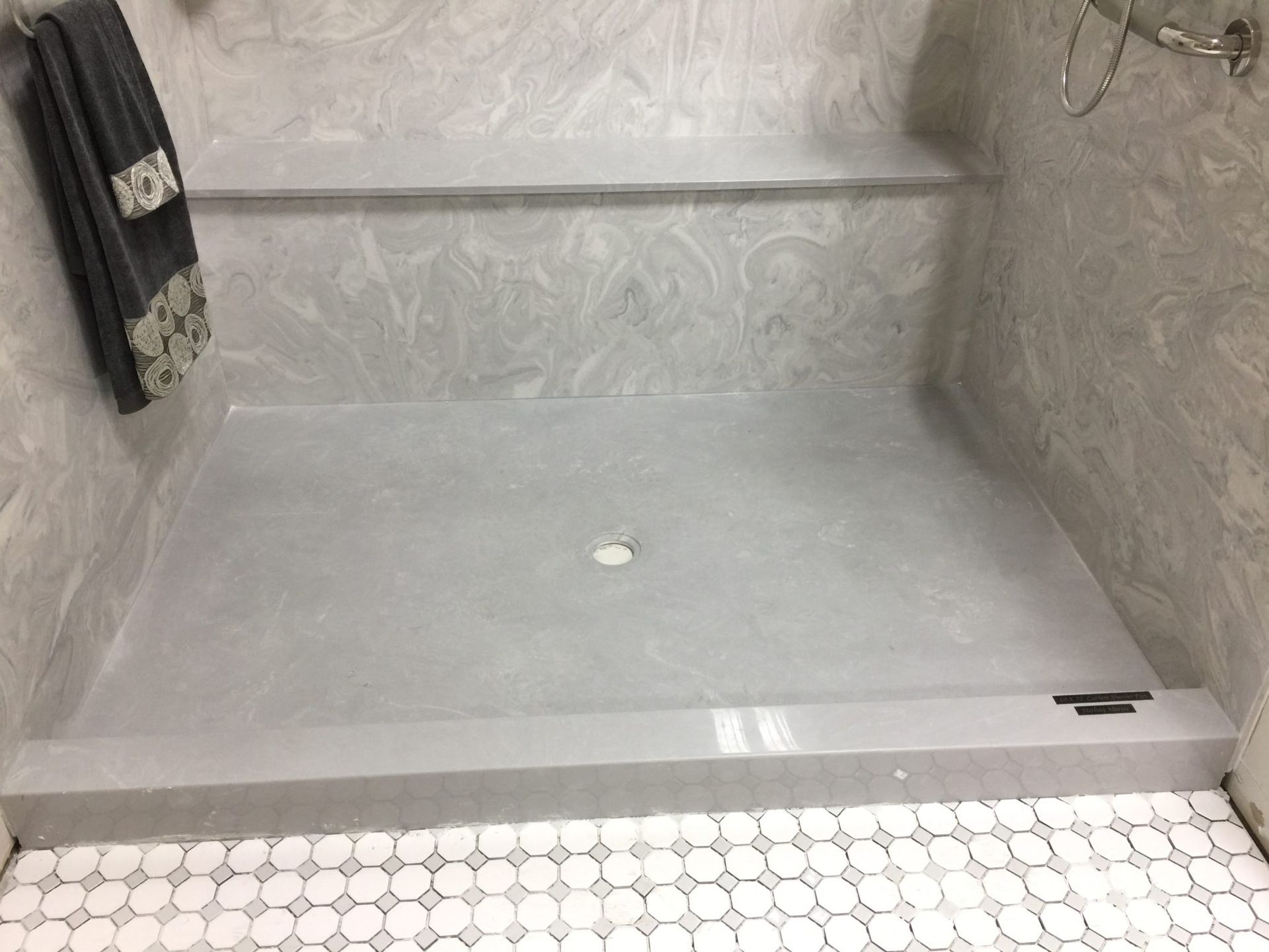 A bathroom with a walk in shower and a towel hanging on the wall.