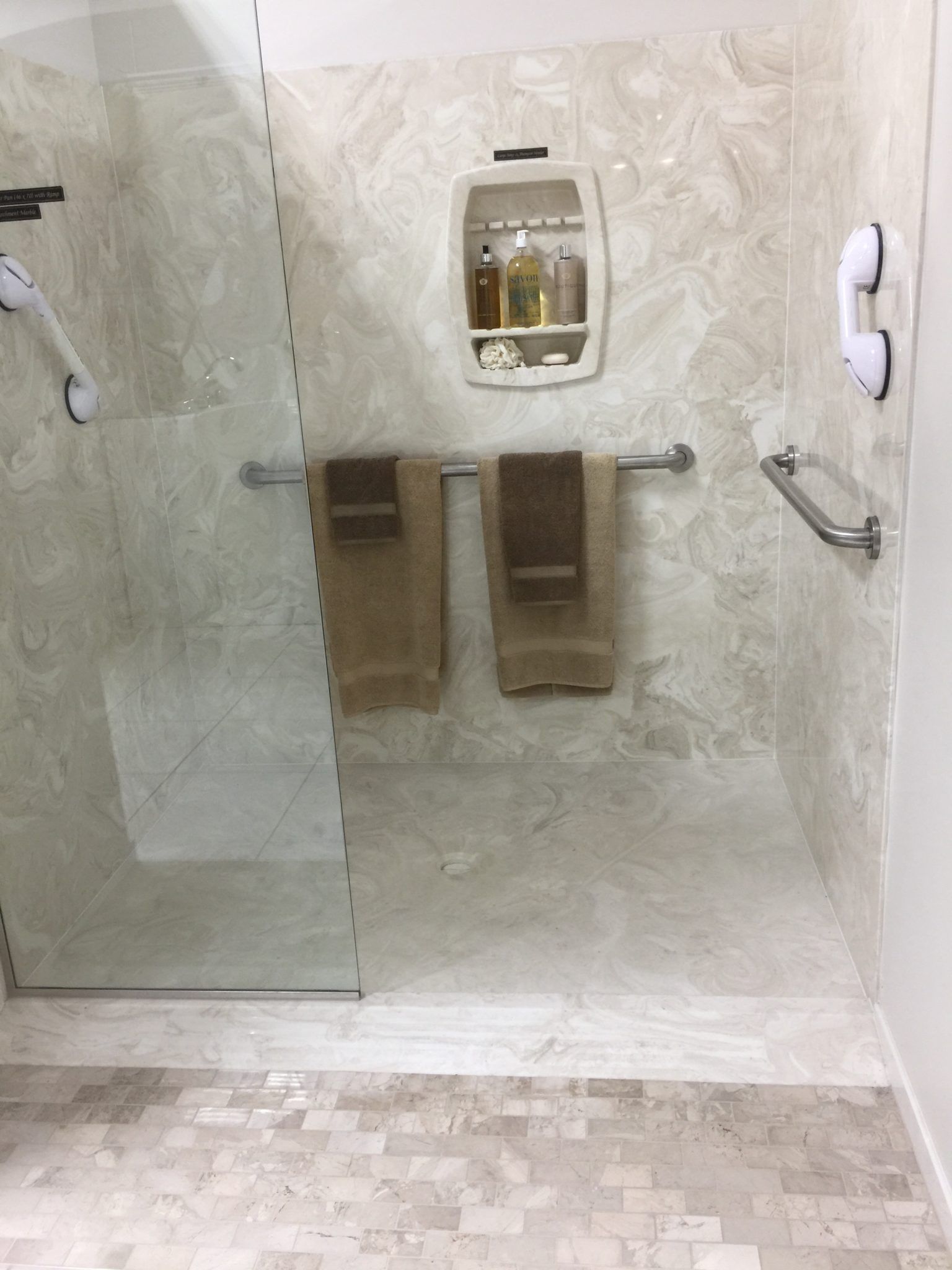 A bathroom with a walk in shower and two towels hanging on the wall.