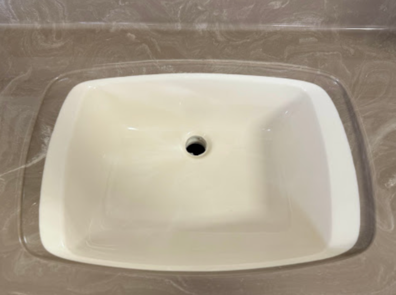 A white bathroom sink is sitting on top of a marble counter.