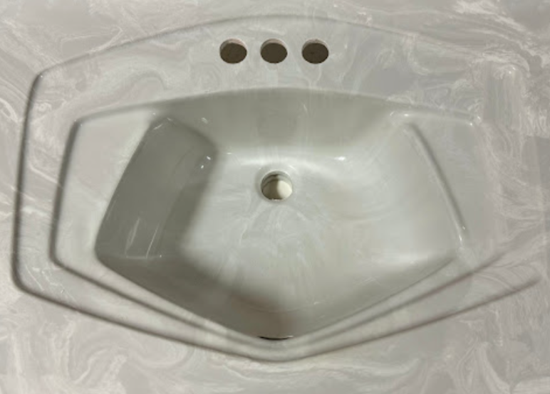 A white bathroom sink with three faucets and three holes in it.