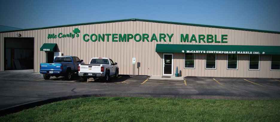 Two trucks are parked in front of a building that says contemporary marble