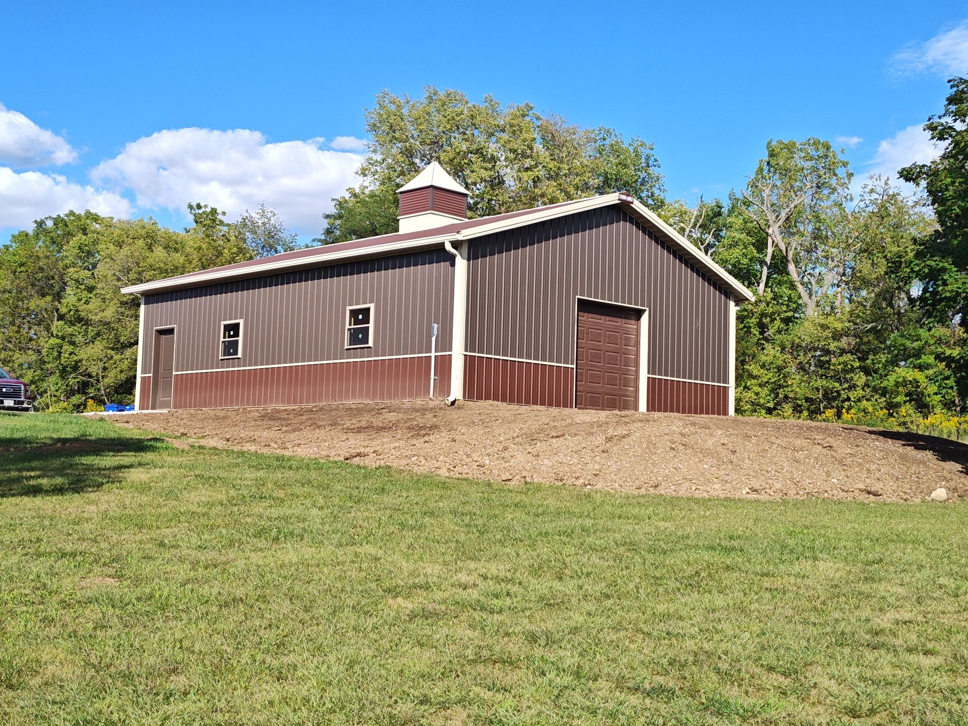 Brown building appears to be an indoor horse arena or barn.