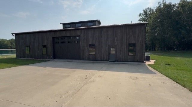 A large barn with a garage and a driveway in front of it.