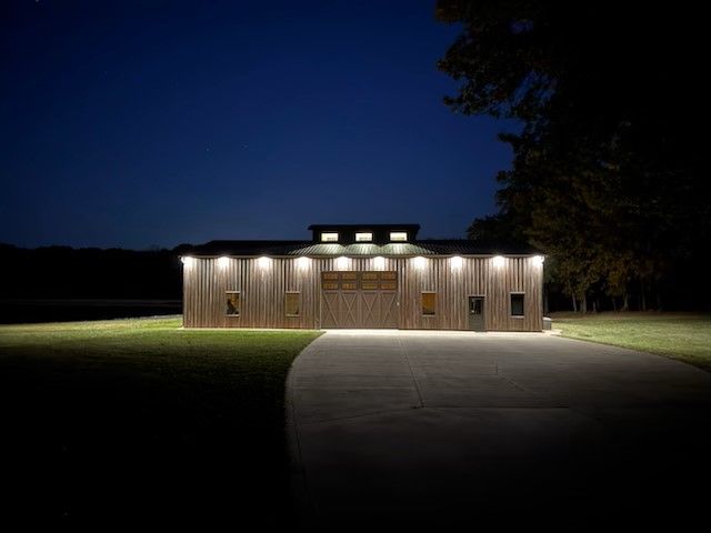 A large wooden barn is lit up at night.