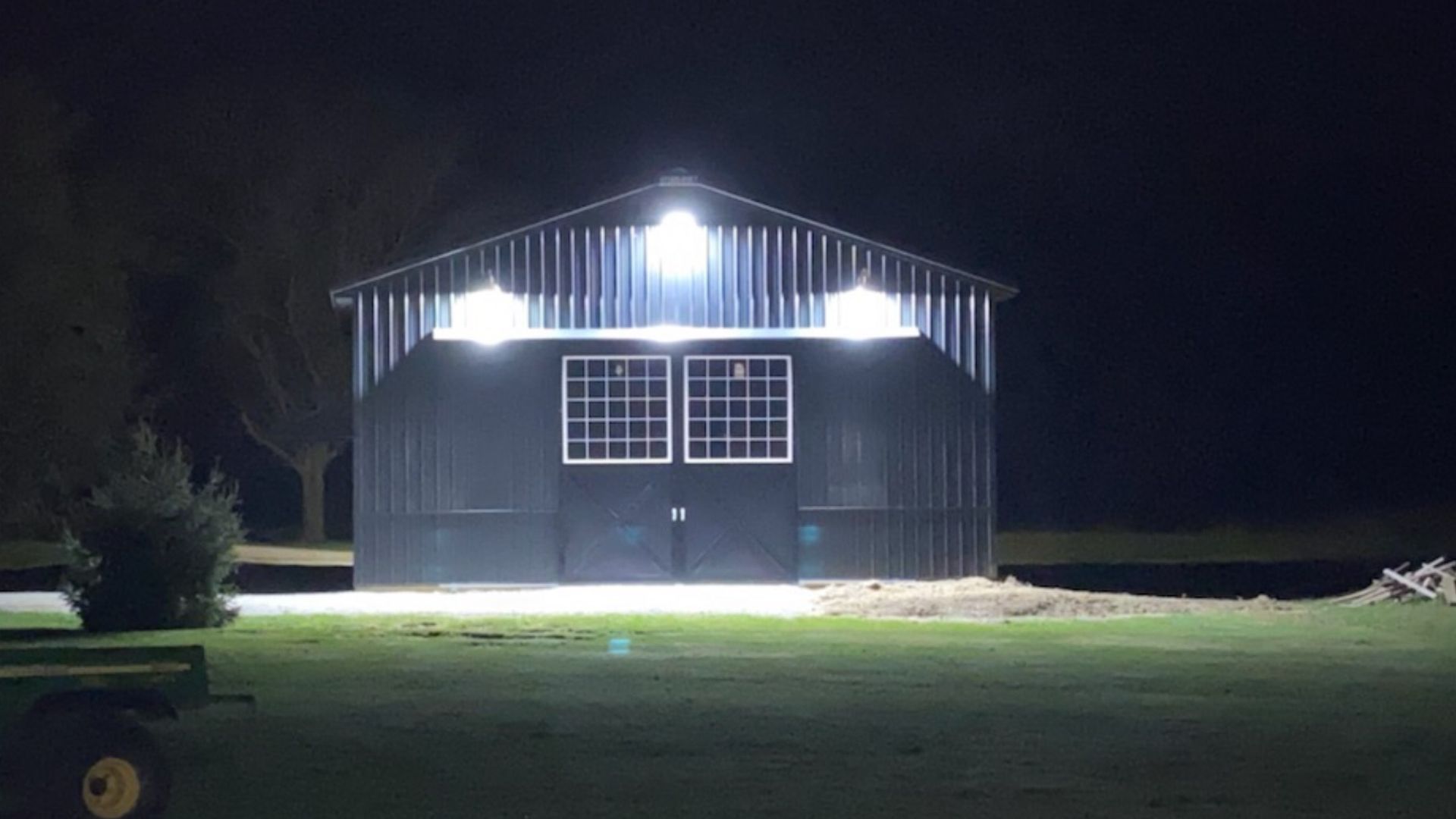 A barn is lit up at night with a lot of lights on it.