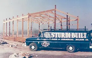 A Sturdi-Built truck is parked in front of a building under construction