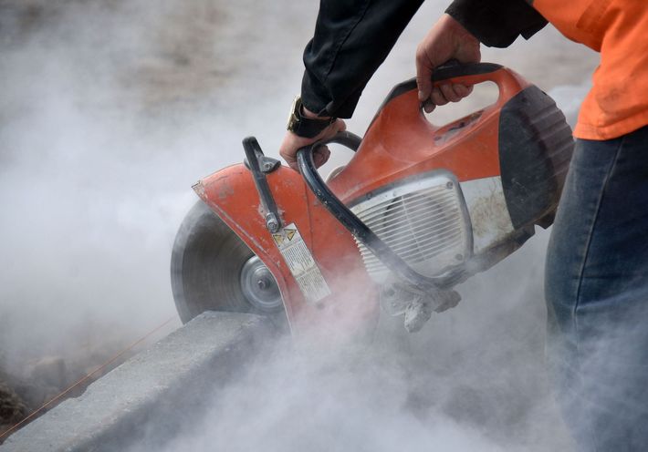 A man is using a circular saw to cut concrete.