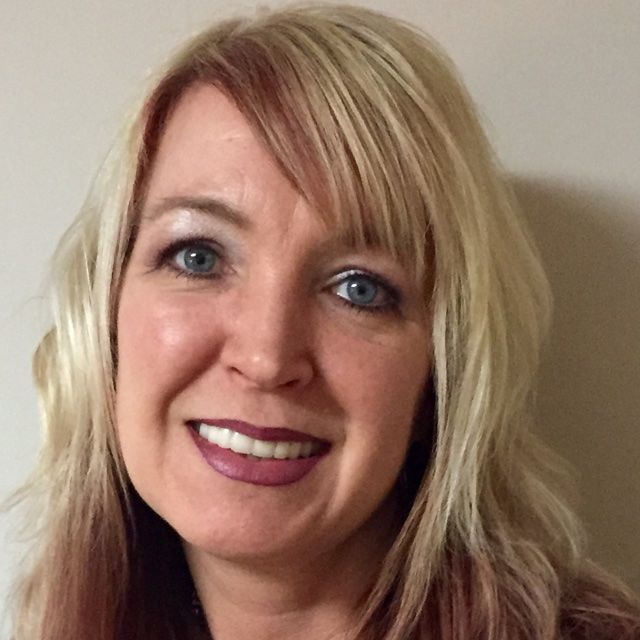 A woman with blonde hair and blue eyes smiles for the camera