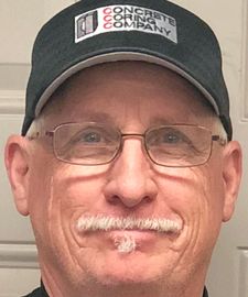 A man wearing glasses and a hat is smiling for the camera.