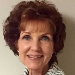 A woman with brown hair and blue eyes smiles for the camera