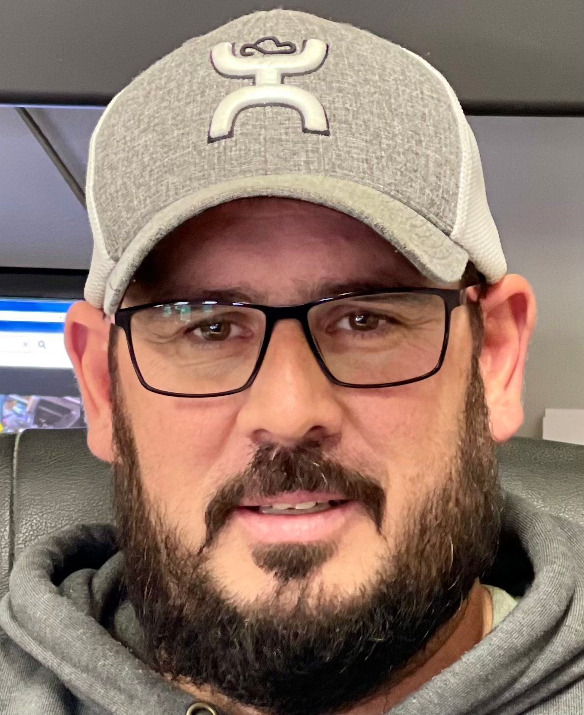 A man with a beard and glasses is wearing a hat.