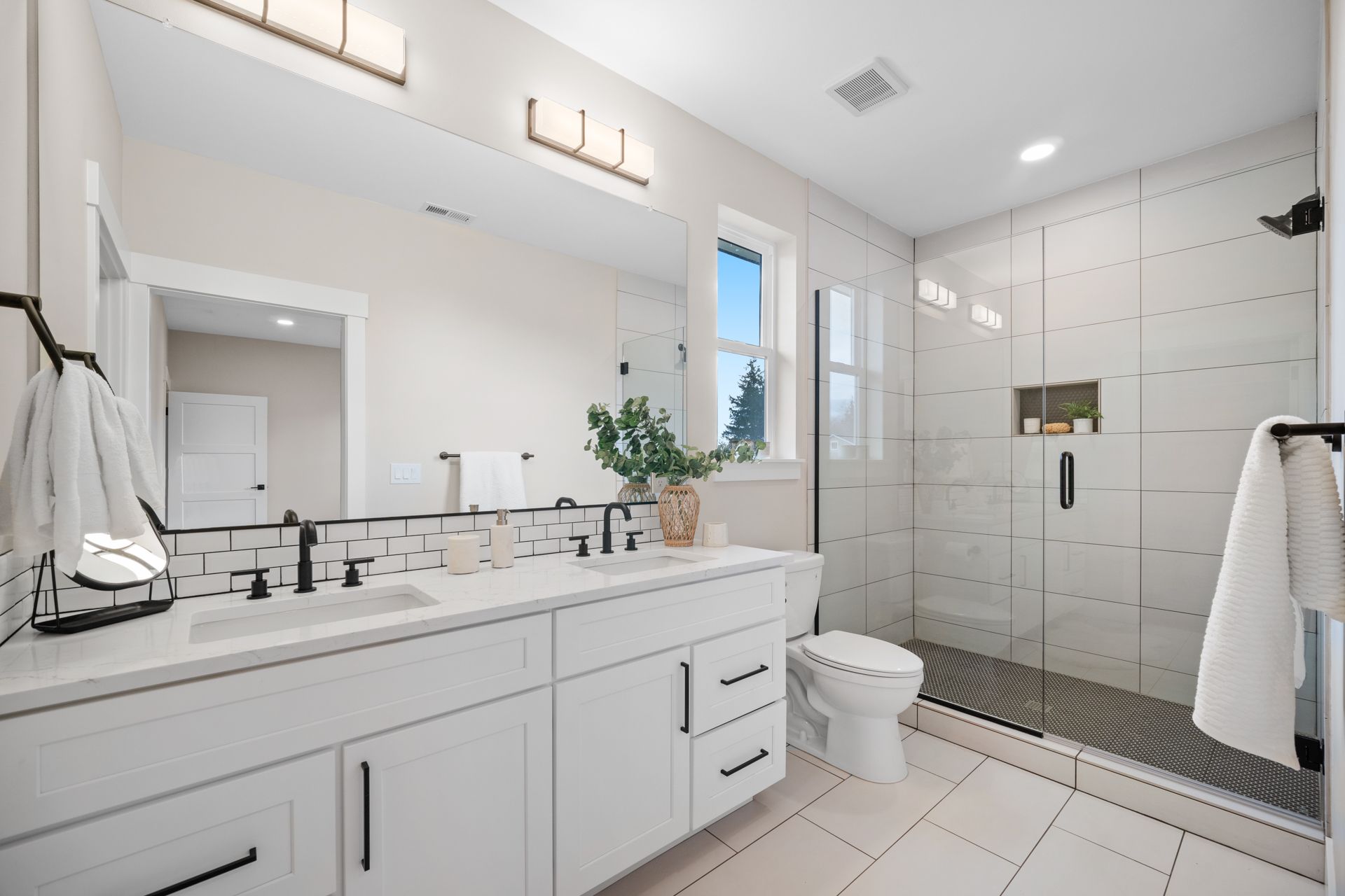 A bathroom with a toilet , sink , mirror and walk in shower.