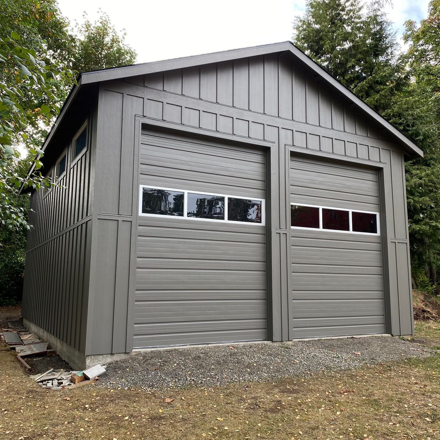 A large gray garage with two garage doors and a roof.