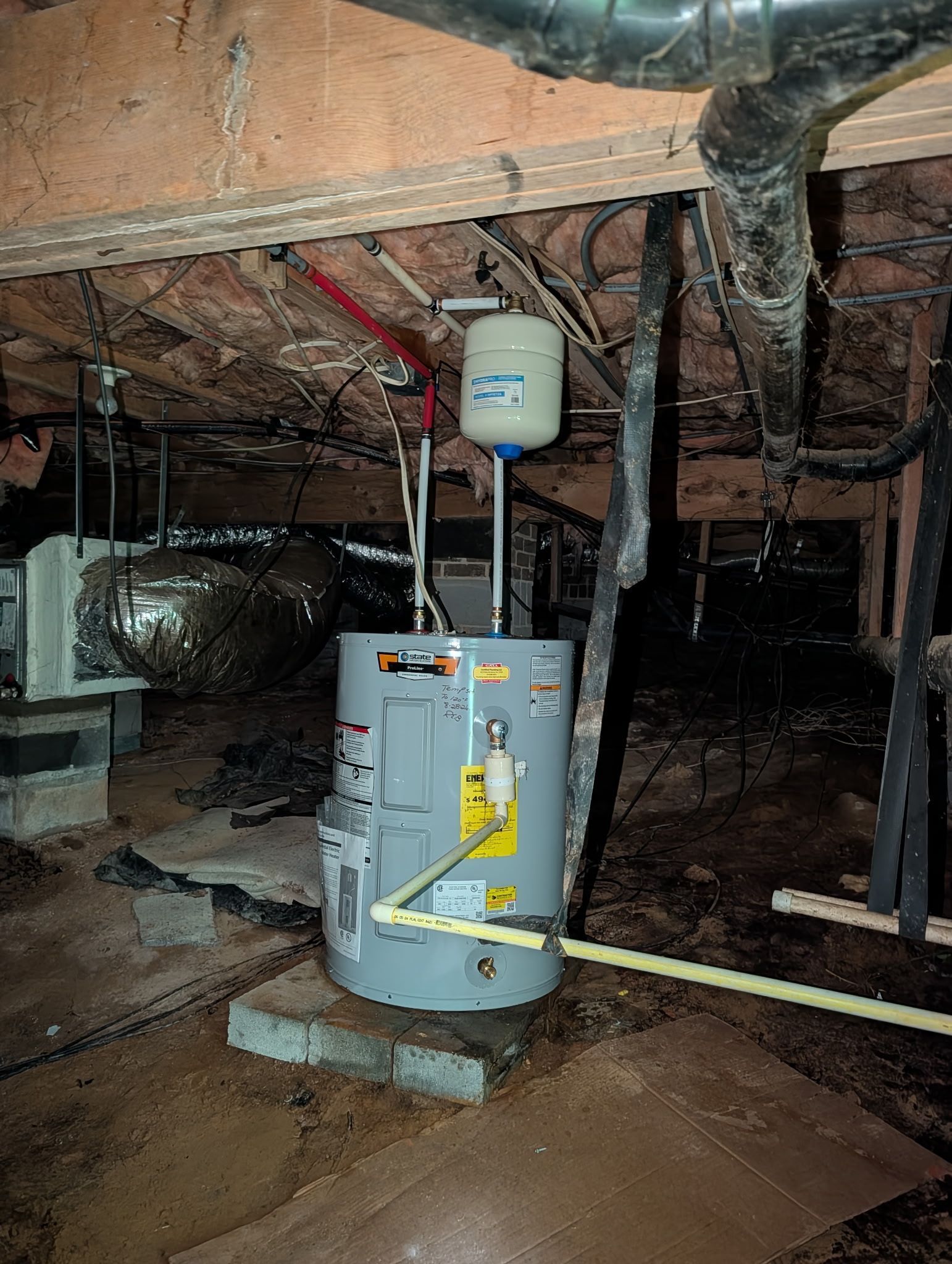 Water heater and HVAC furnace in a crawlspace with exposed ductwork and insulation.