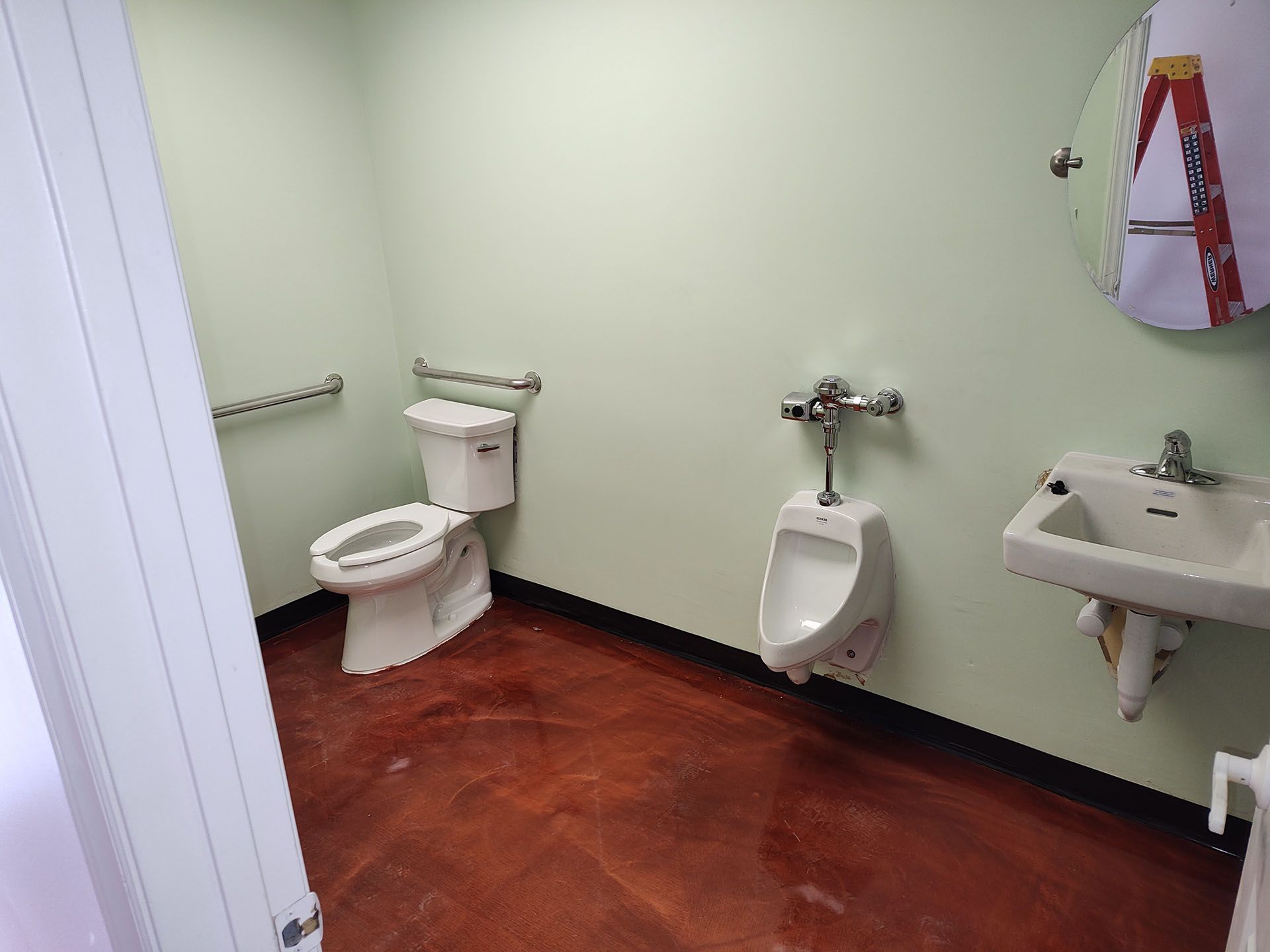 Public restroom with toilet, urinal, sink, and metallic floor.