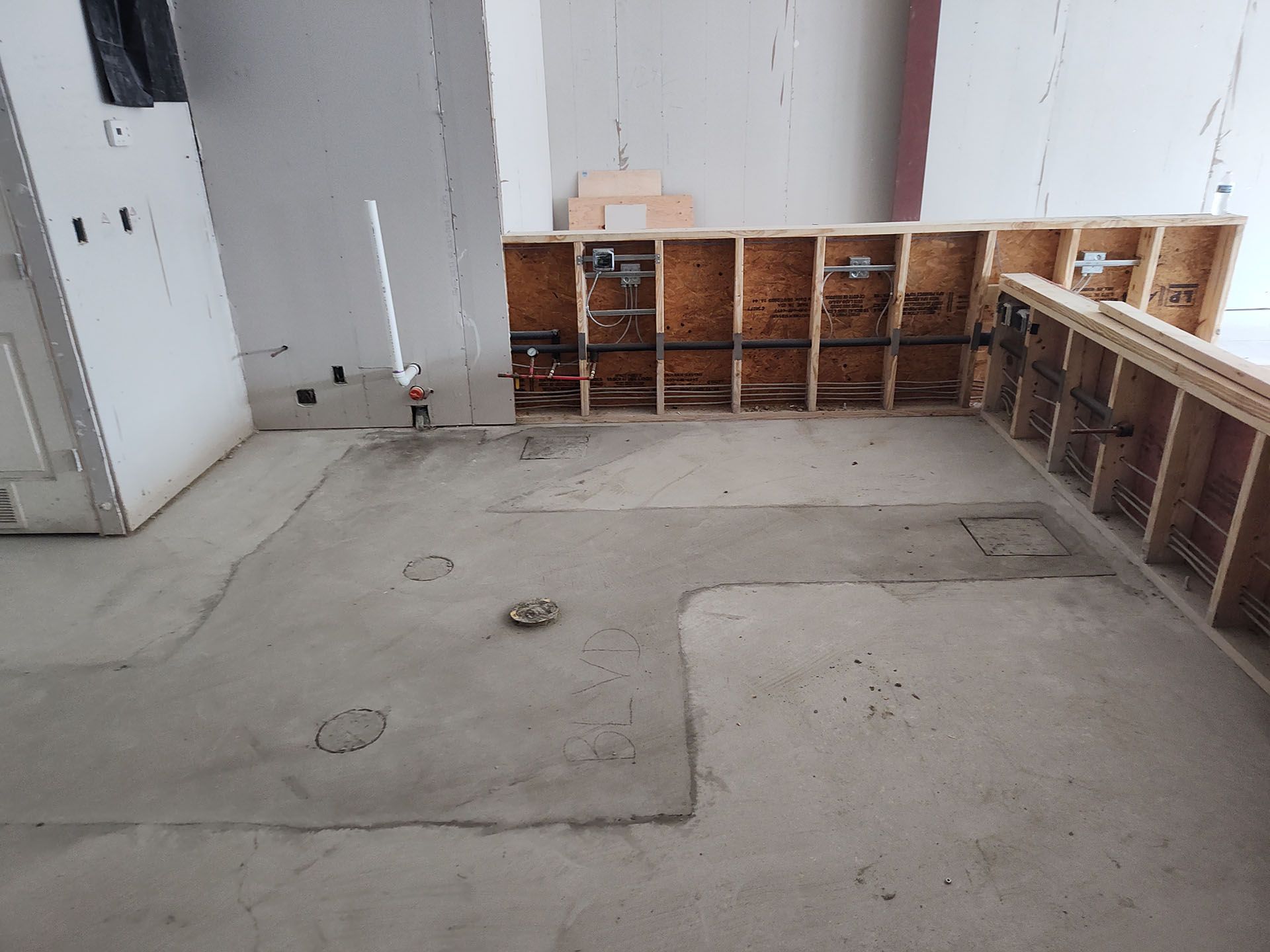 Concrete floor with unfinished wooden wall framing; plumbing pipes visible.
