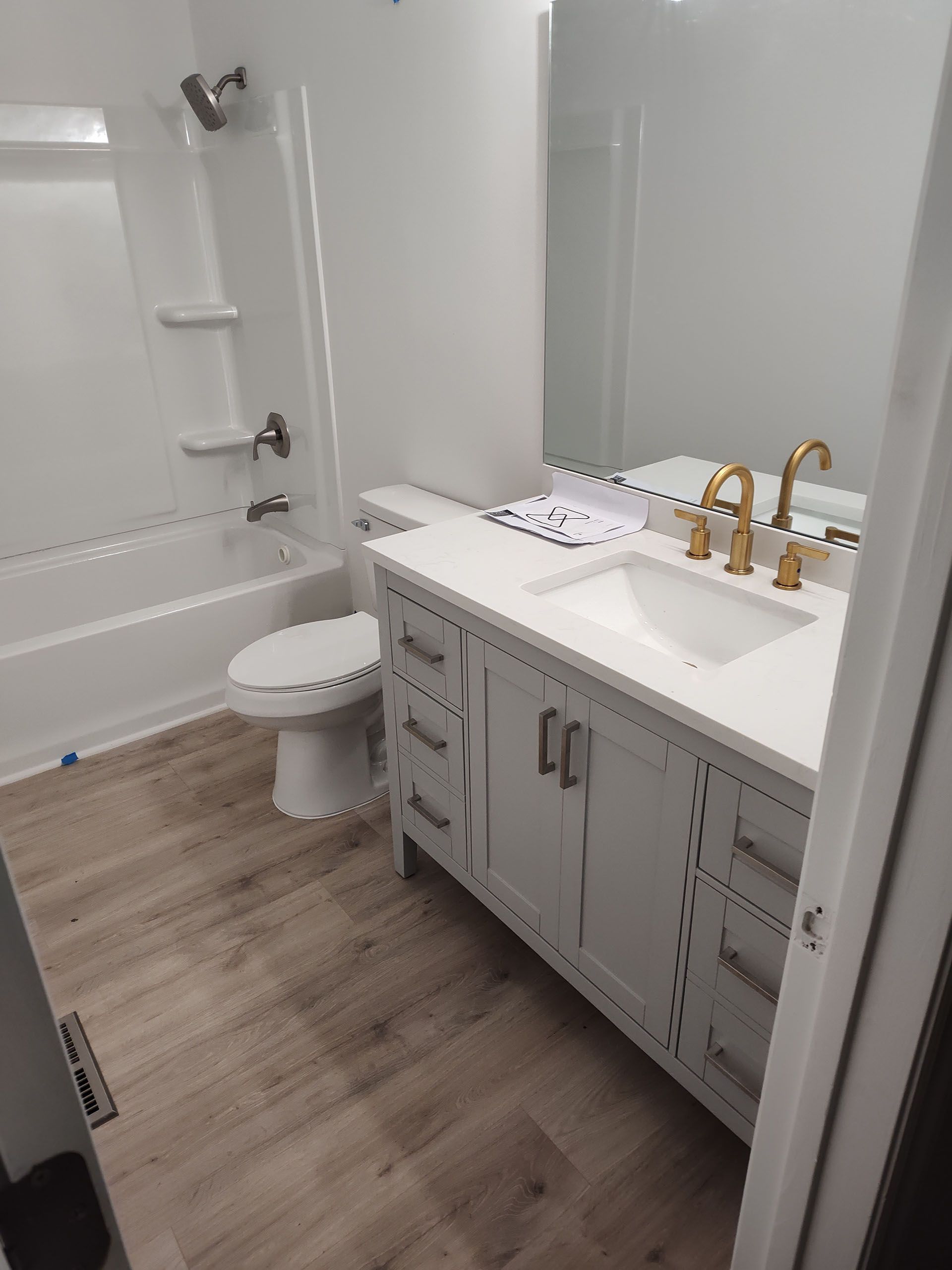 White bathroom with a vanity, toilet, and bathtub. Beige flooring.