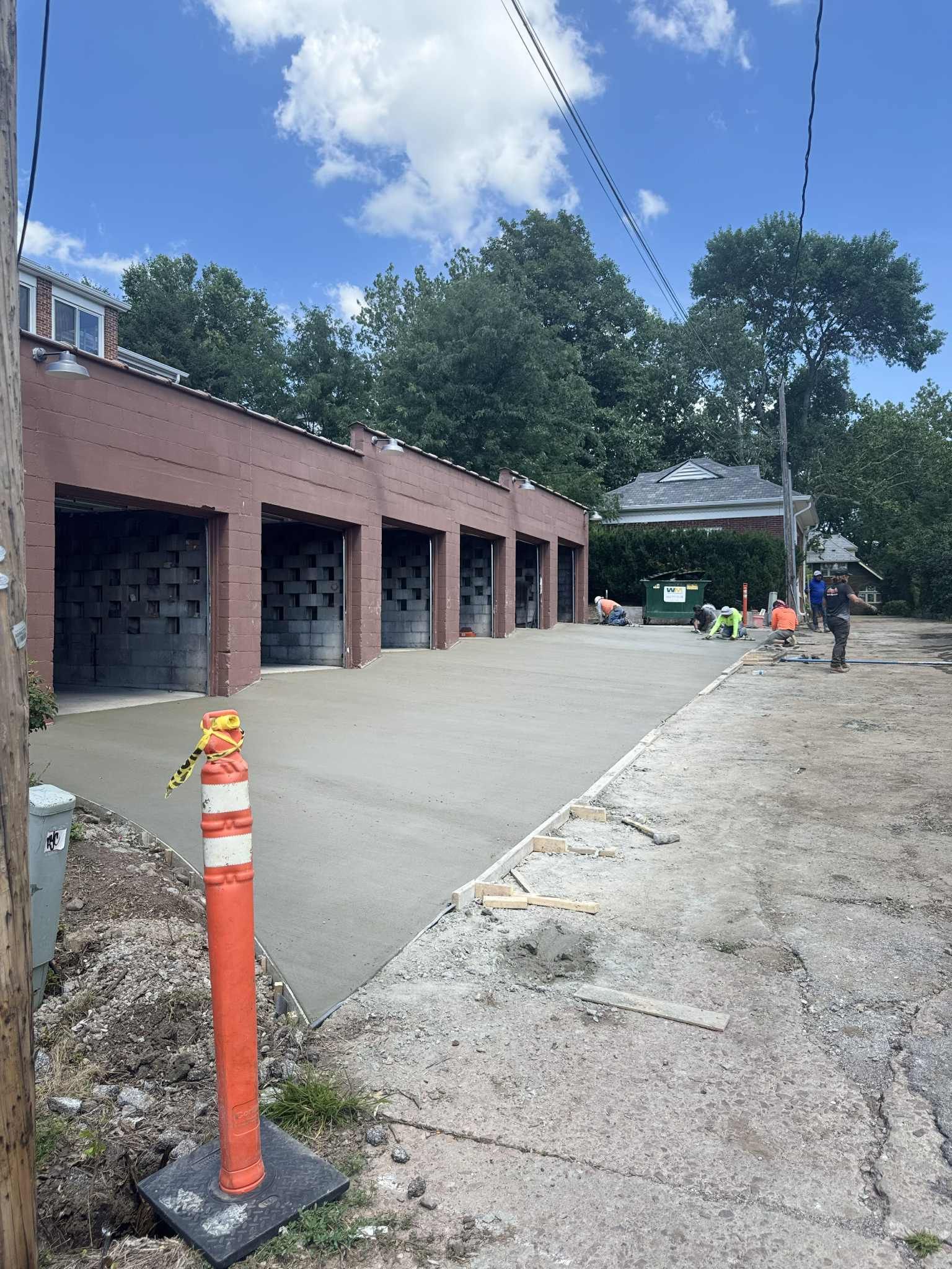 New concrete driveway and garage bays under construction; blue sky, sunny day.