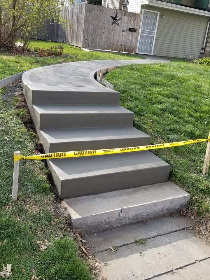 Newly constructed concrete steps and walkway, marked with caution tape, leading up a small hill.