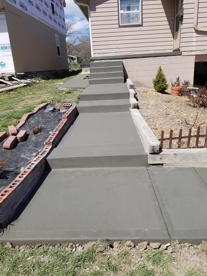 Freshly poured concrete sidewalk and steps leading to a house entrance.