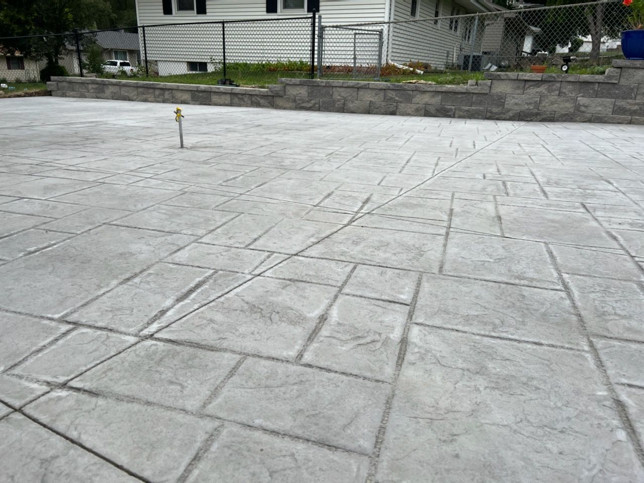Stamped concrete patio with a gray stone pattern in front of a house.