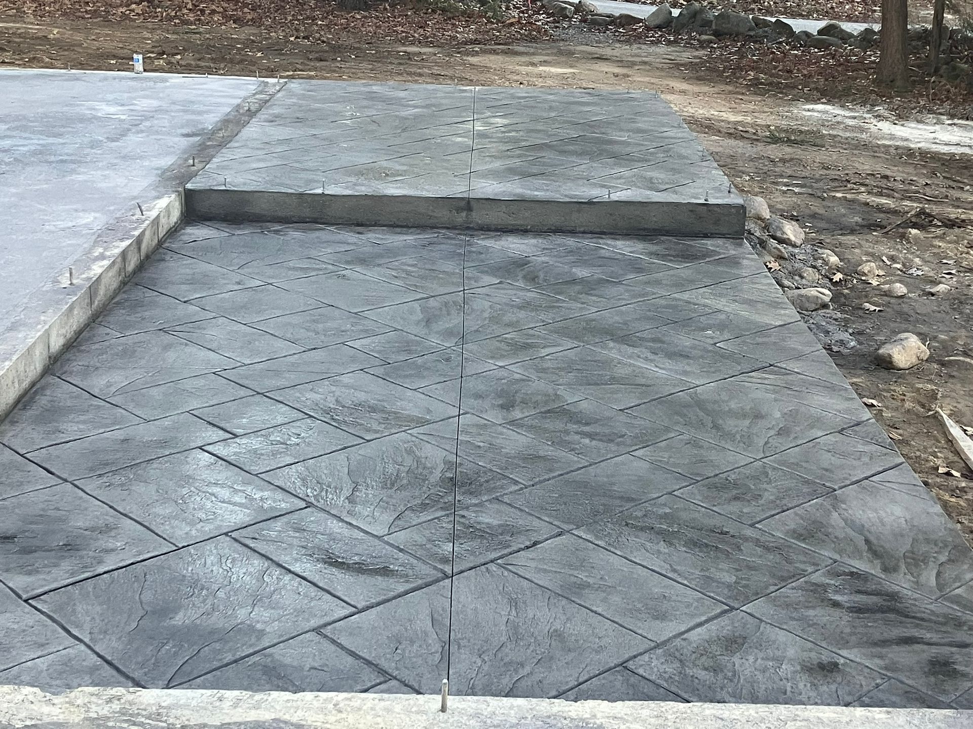 Newly poured concrete patio with patterned design. Gray color, outdoor setting.