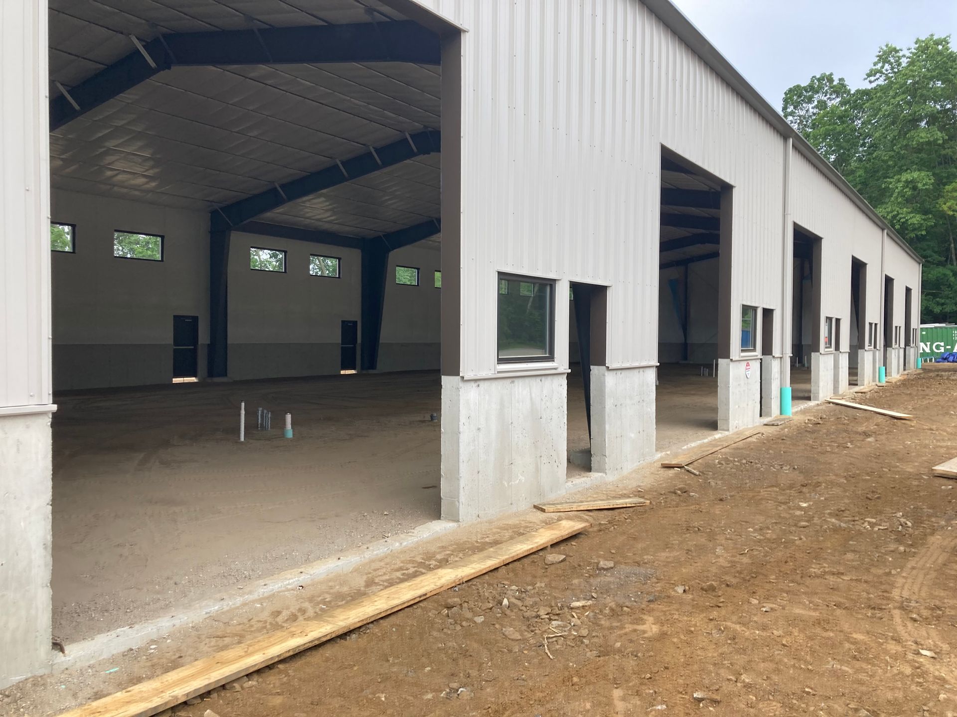 Empty metal industrial building with multiple open bays and concrete base.
