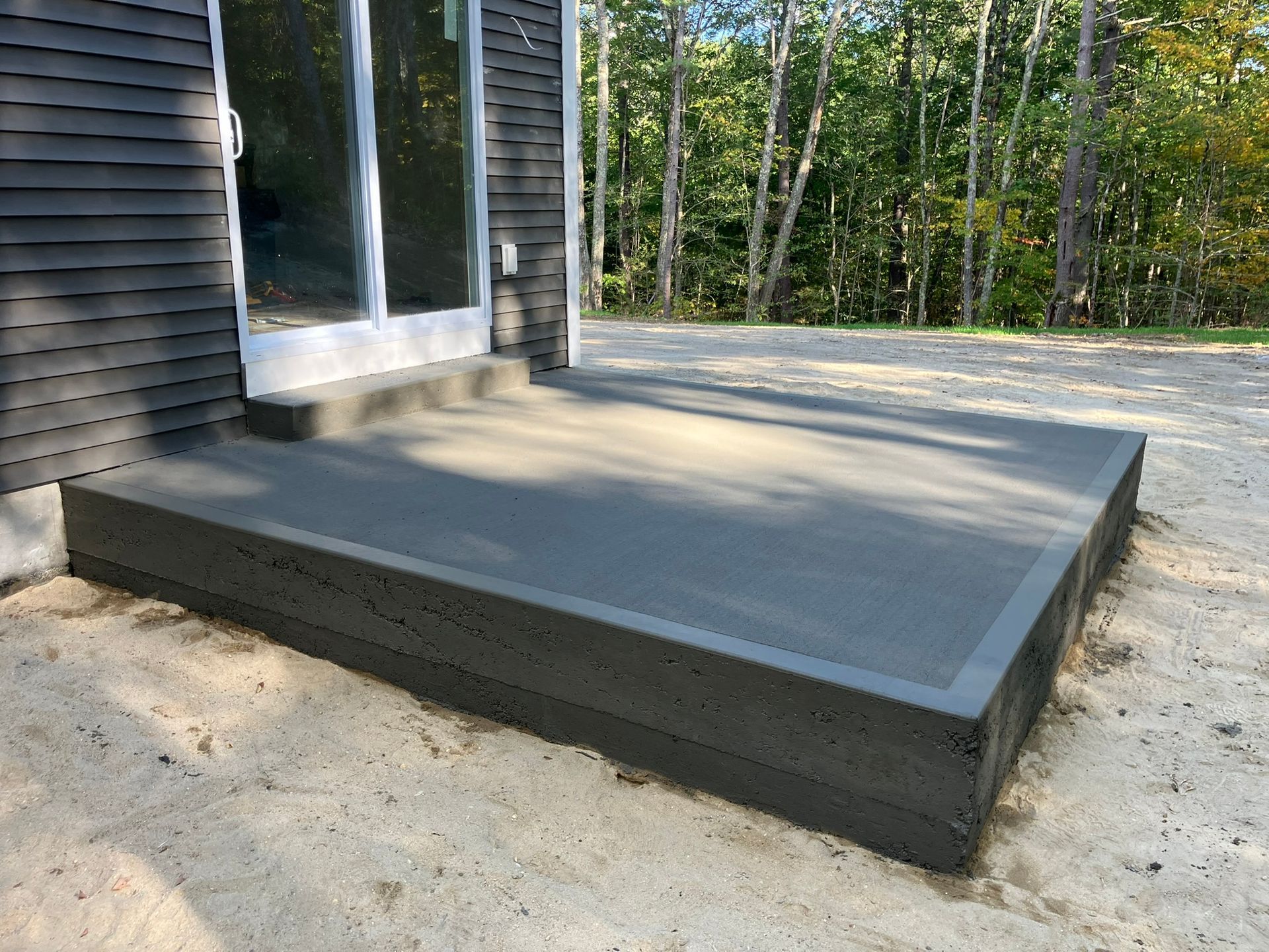 Dark gray concrete porch and step outside a building with a sliding glass door.