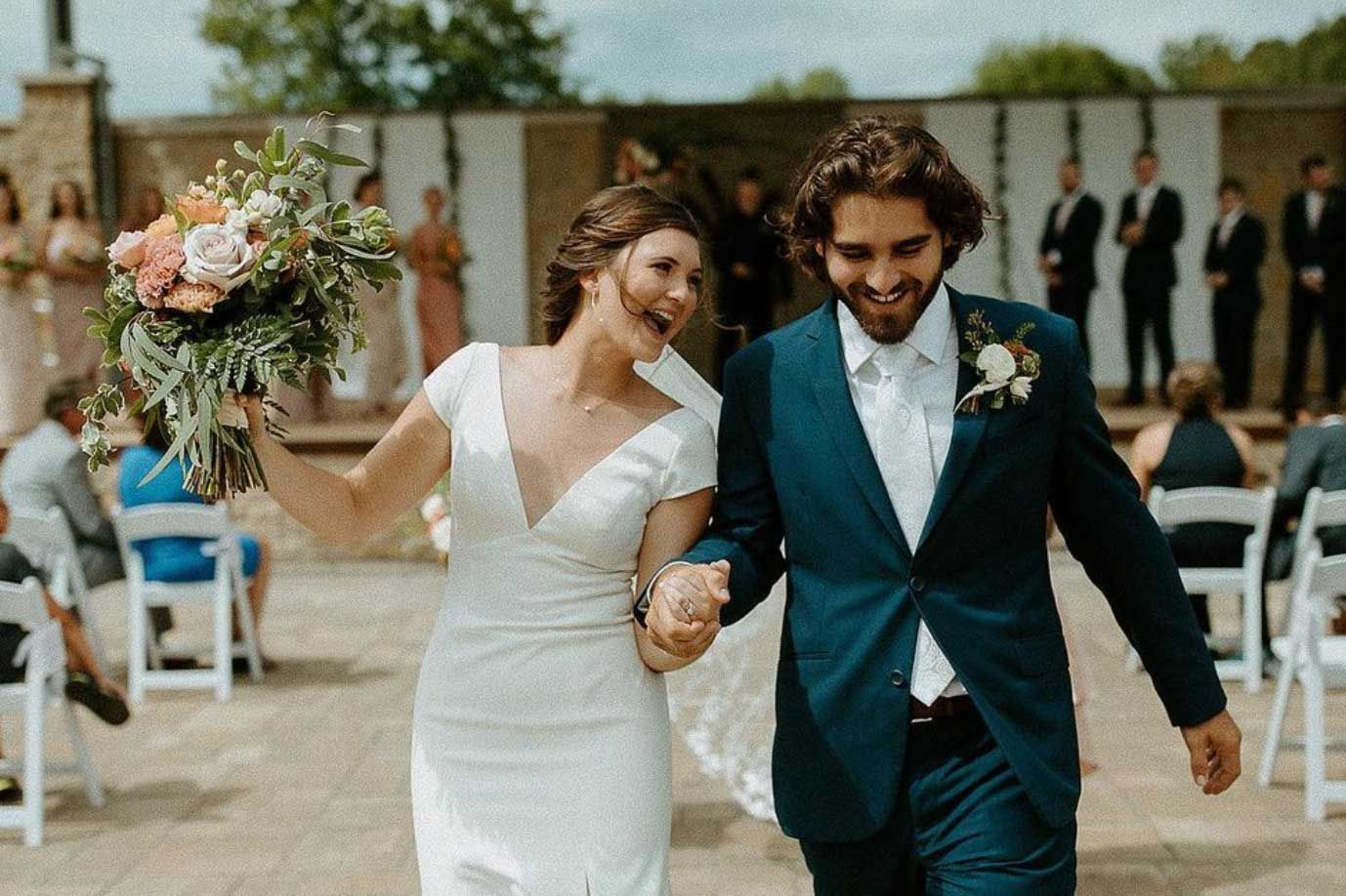 A bride and groom are walking down the aisle at their wedding holding hands.