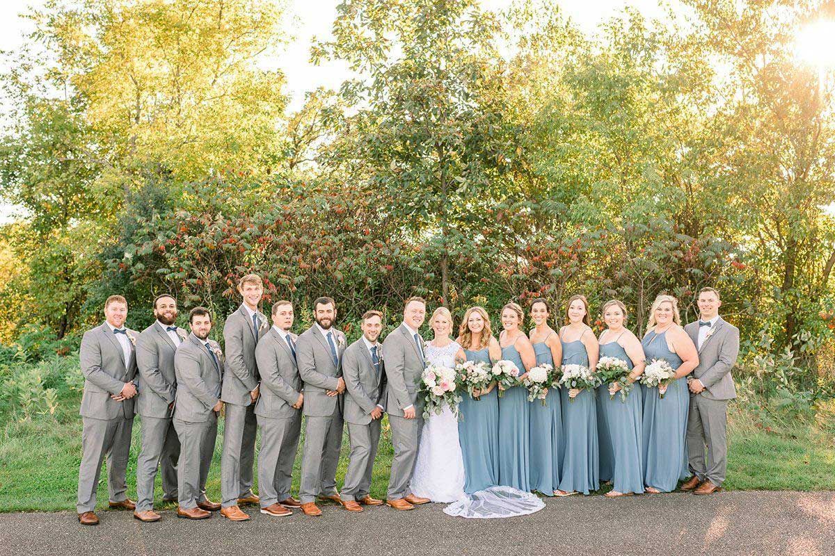 The bride and groom are posing for a picture with their wedding party.