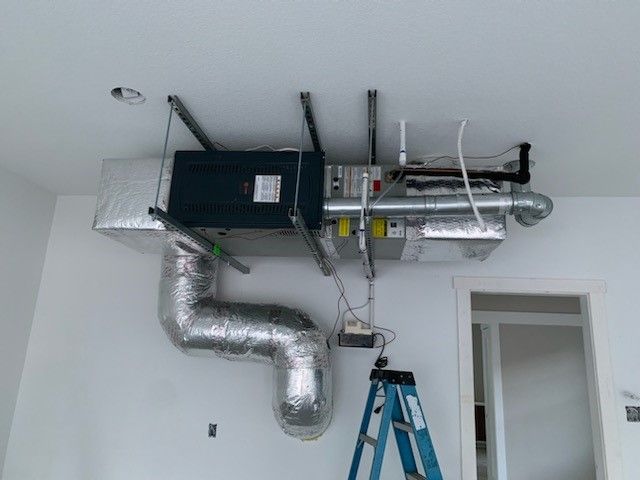 A room with a ladder and a ventilation system hanging from the ceiling.