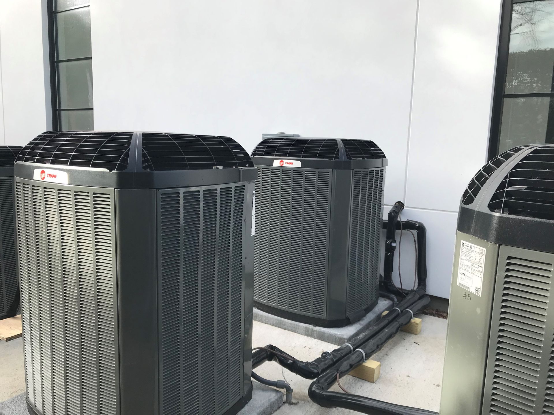 Three air conditioners are sitting next to each other on the side of a building.