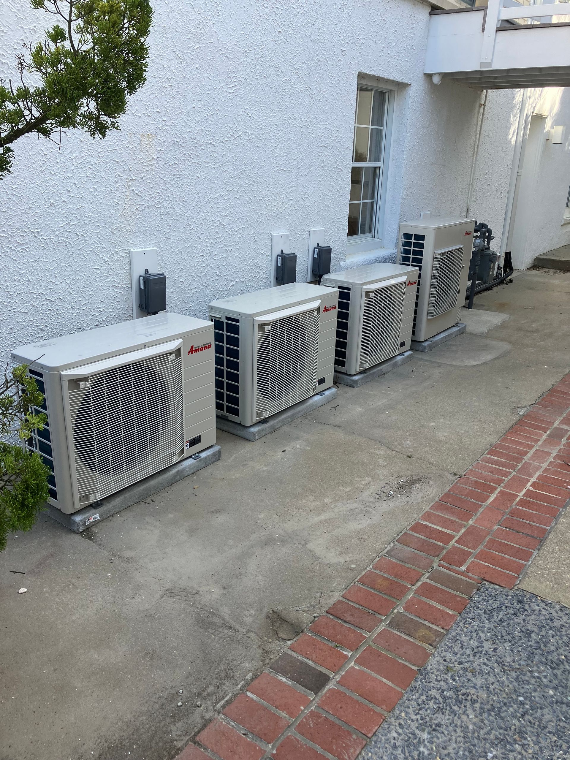 A row of air conditioners are sitting on the side of a building.