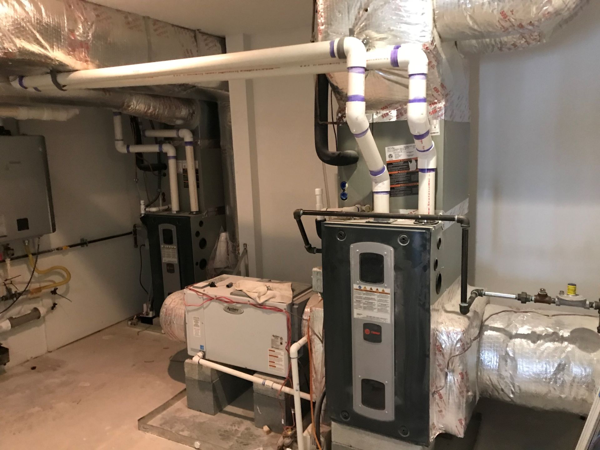 A room with a lot of pipes and a heater in it.