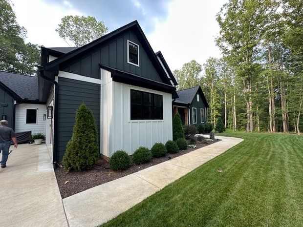 Black-and-white modern house with manicured lawn and trees along the side yard