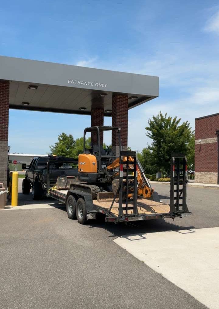 Truck carrying construction equipment at a building entrance under a blue sky