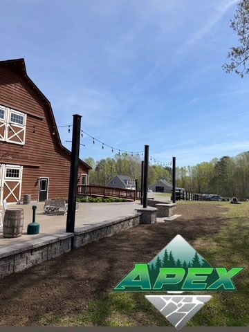 Outdoor patio beside a brown building with black posts and string lights under a blue sky, with an APEX logo overlay.