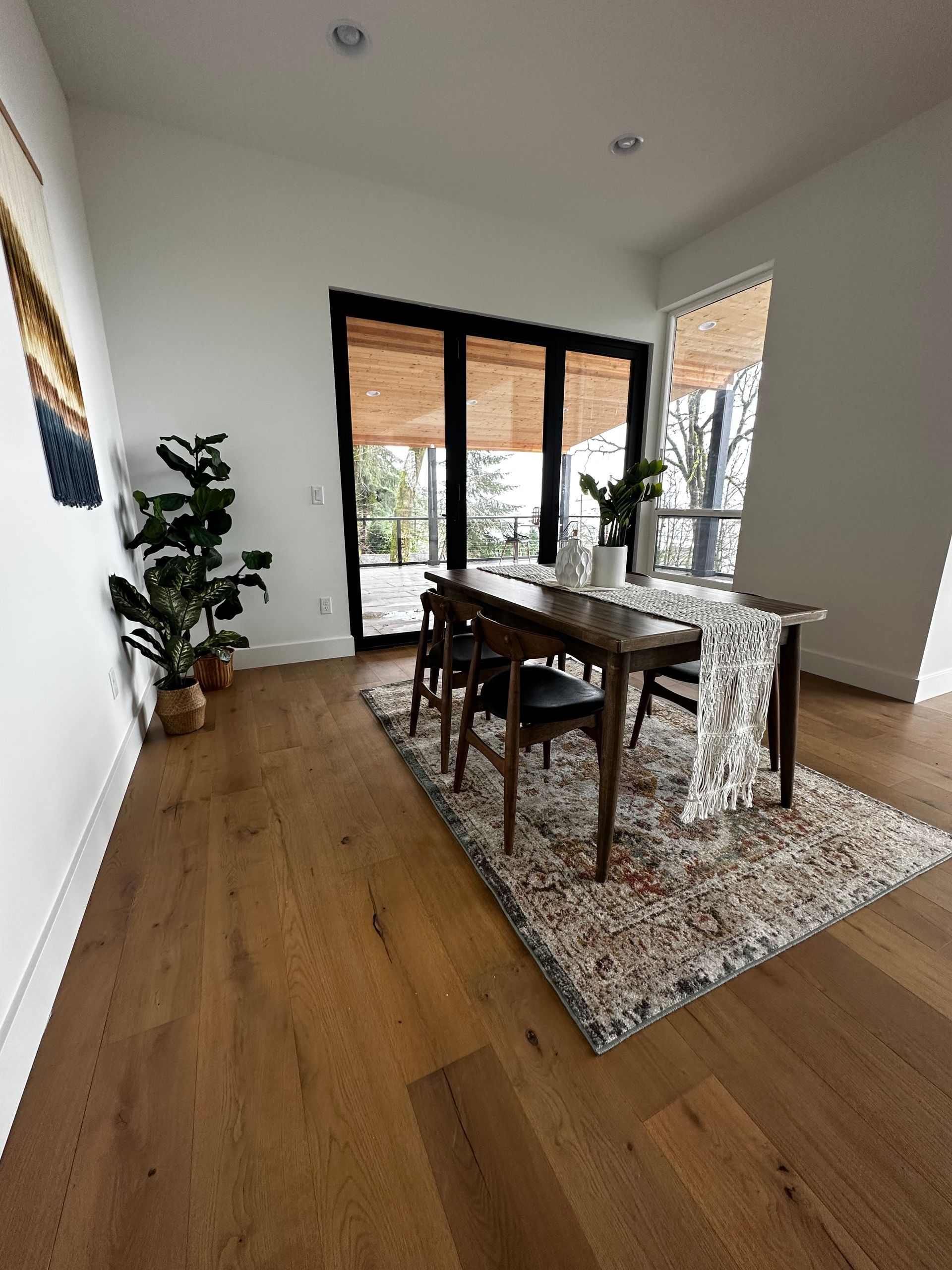 Dining room with wood floor, table, chairs, plants, and sliding glass doors.