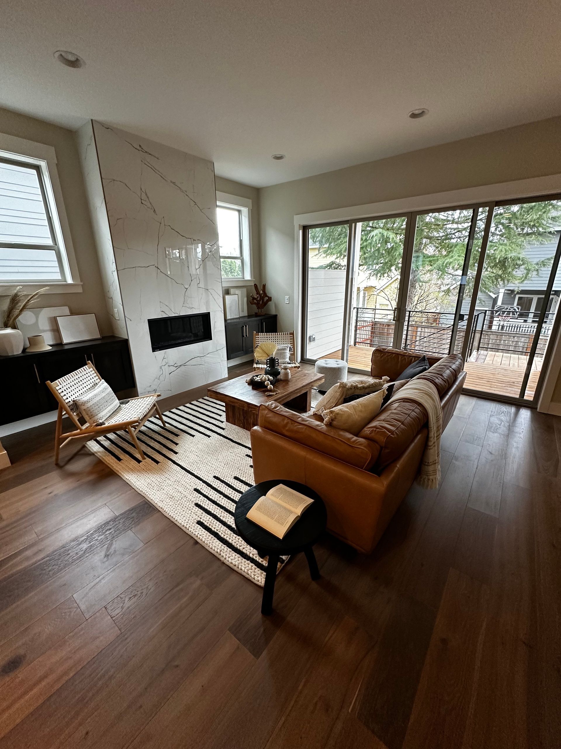 Living room with leather sofa, marble fireplace, and sliding glass doors to a deck.