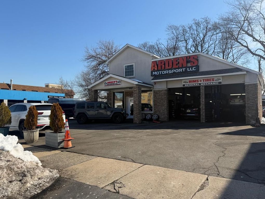 Autobody shop storefront with trucks parked outside on a sunny day