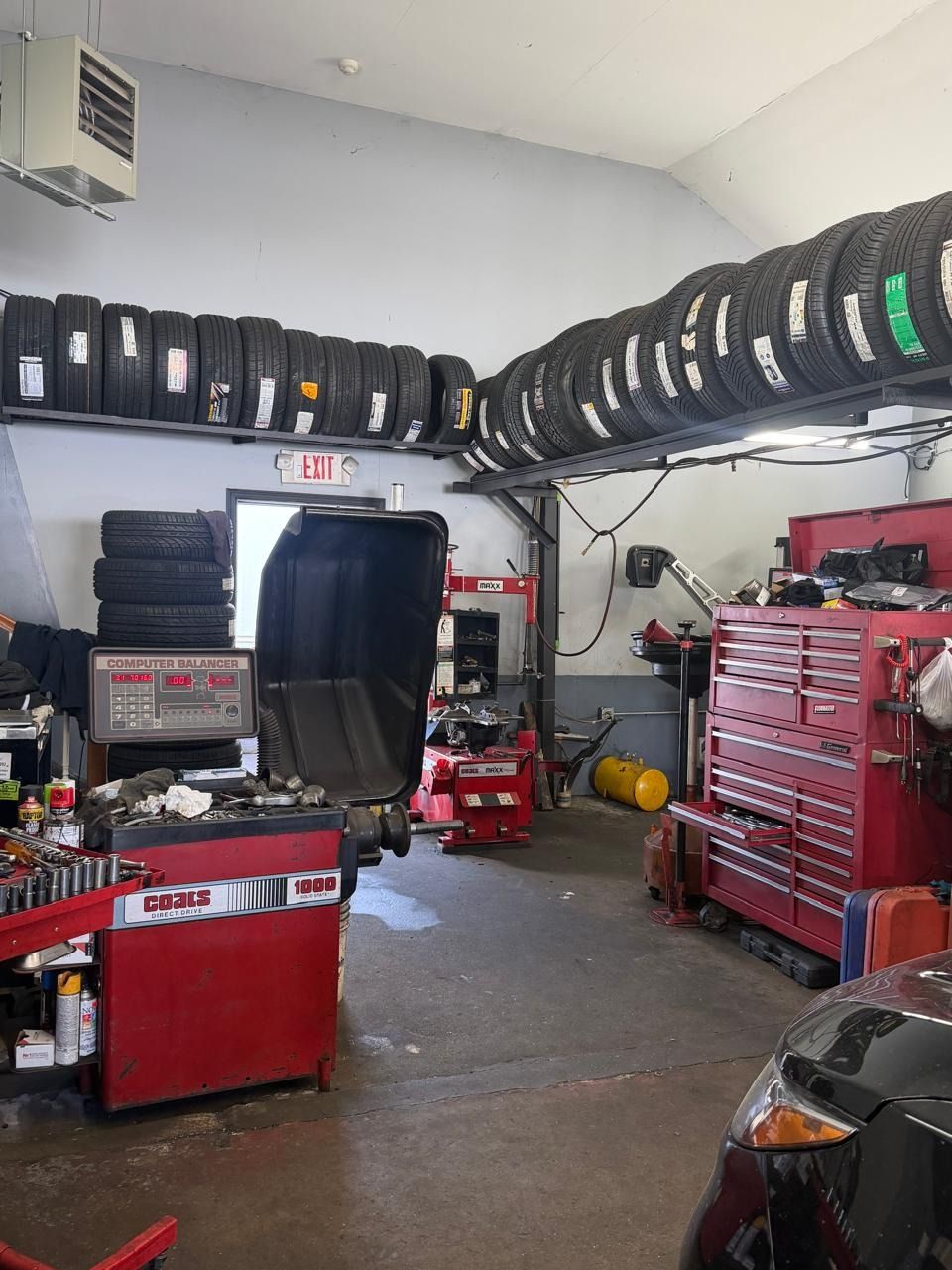 Auto repair shop with tires stacked on shelves, red tool cabinets, and equipment in a cluttered garage