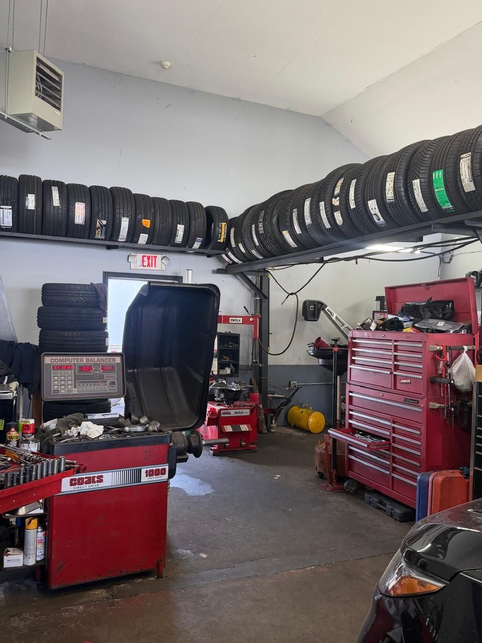 Auto repair shop with stacked tires, red tool cabinets, and car equipment in a garage.