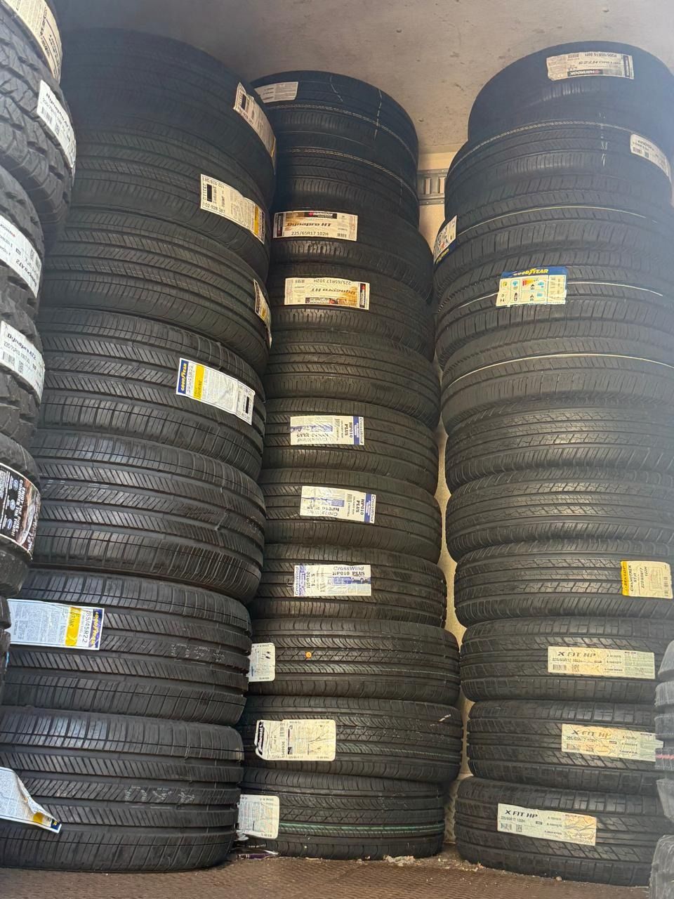 Stacks of black tires piled vertically in a warehouse or storage yard.