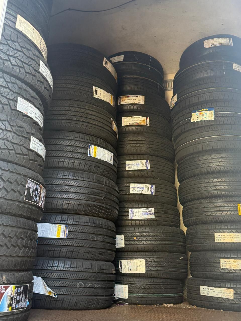 Stacks of black tires piled high in a storage room with a curved ceiling